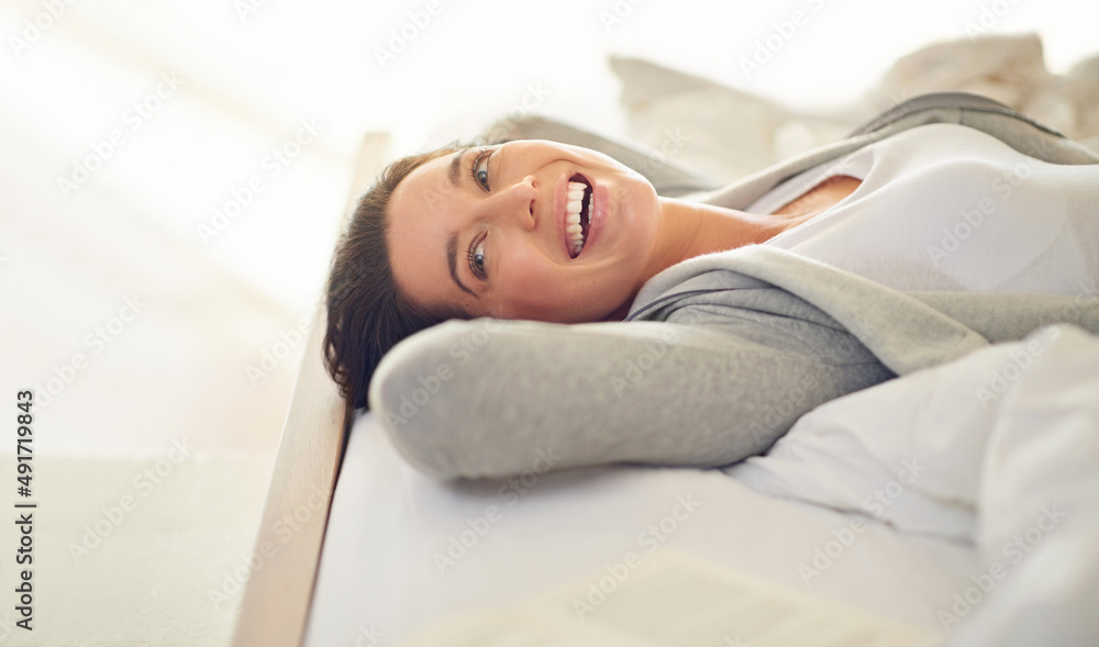 Totally loving this weekend. Cropped shot of a young woman laughing while lying on her bed.