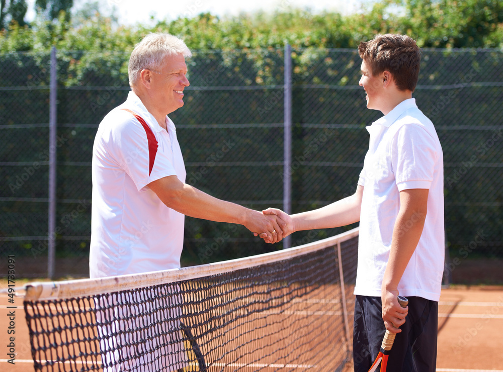 Good game son. A father and son shaking hands after a friendly game of tennis.