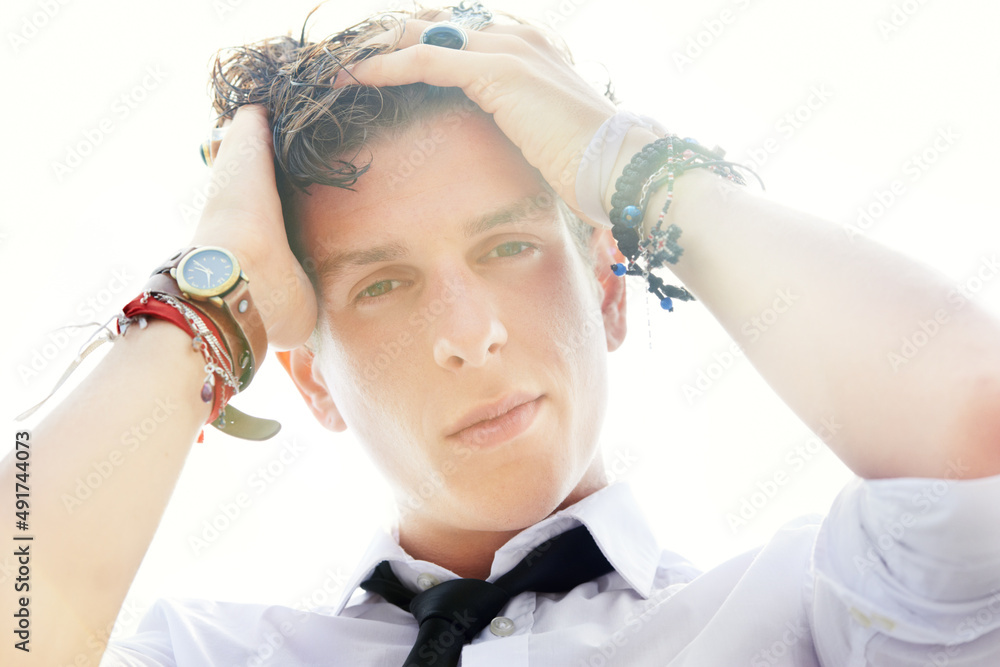 His style is steamy. Low angle portrait of a handsome and stylish young man running his hand through