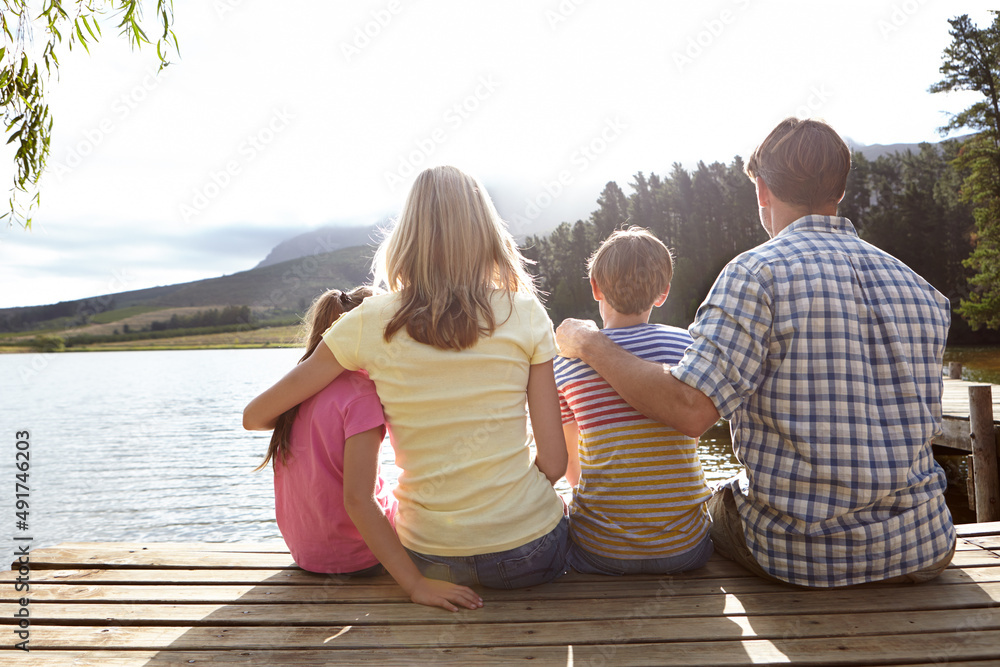 Bonding over natural beauty. Rear view shot of a family sitting on a pier out on a lake in the count