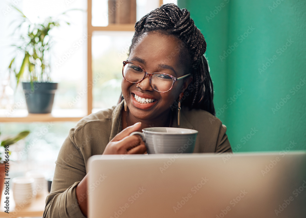 Call it my little coffee shop office. Shot of a young woman having coffee and using a laptop at a ca