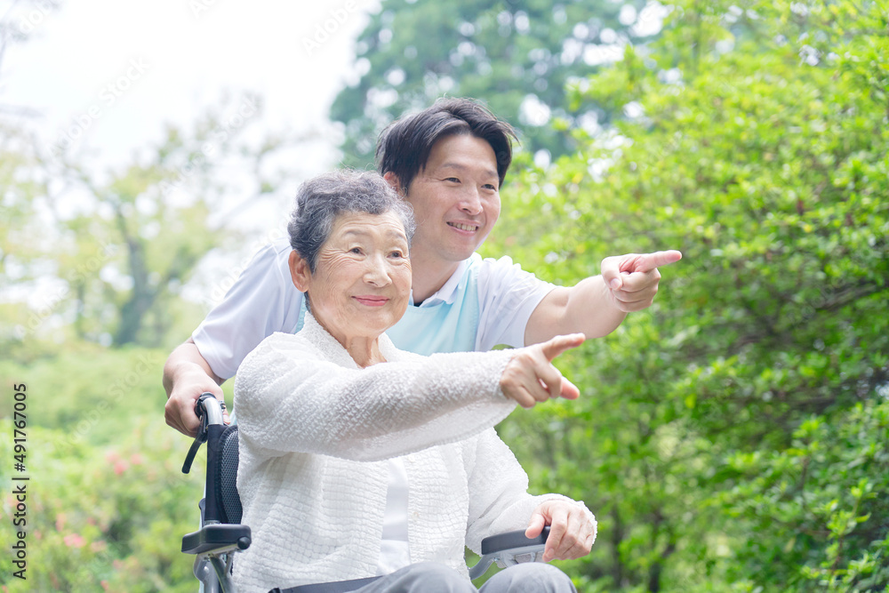 車椅子に乗った高齢者と介護士　屋外