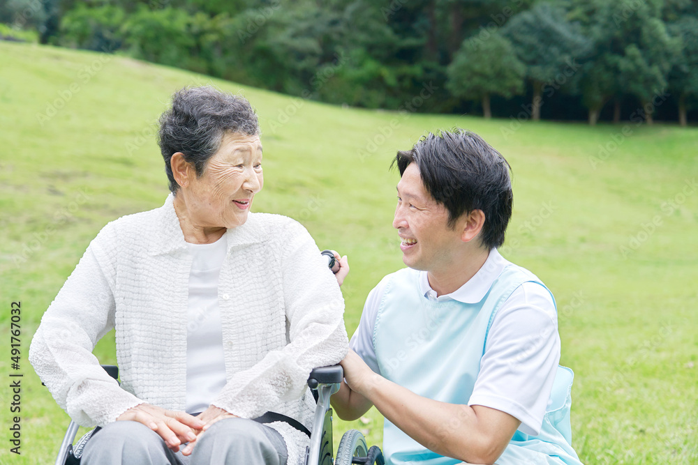 車椅子に乗った高齢者と介護士　屋外