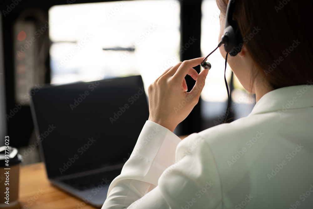 Confident young businesswoman wearing headphones and discussing project details with clients on vide