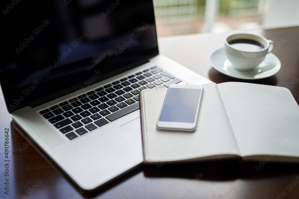 Take a seat and lets get started with success. High angle shot of a laptop, cellphone and notebook o