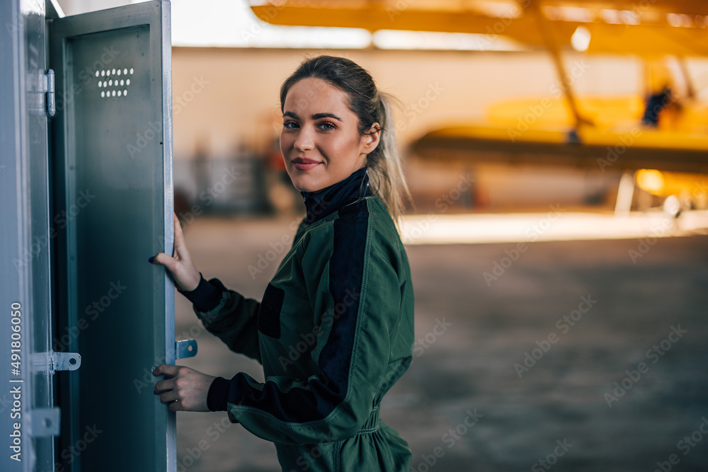 Portrait of happy blonde captain, closing the doors to her locker.