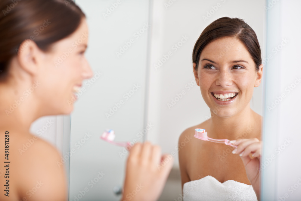 Dental health is important. A young woman standing in front of the mirror brushing her teeth.