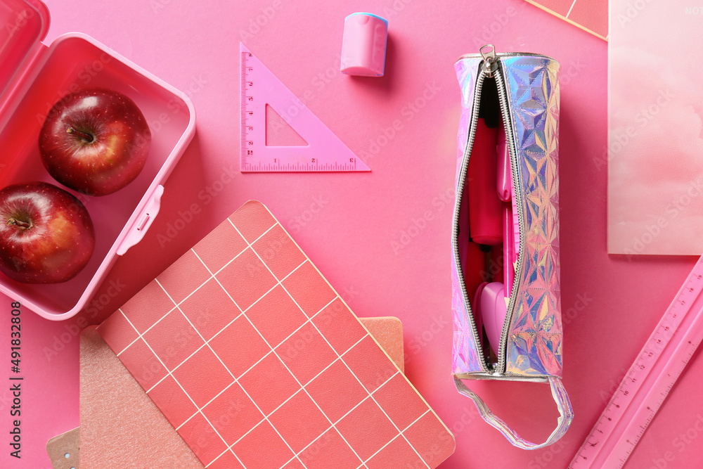 Set of stationery with pencil case and apples on pink background