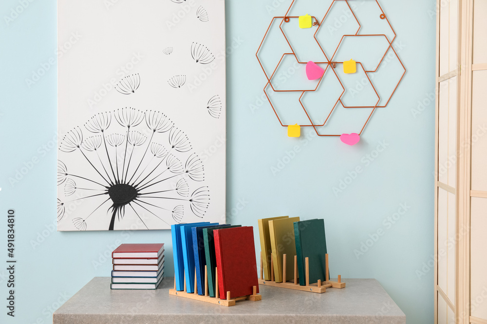 Wooden organizers with books on table near blue wall