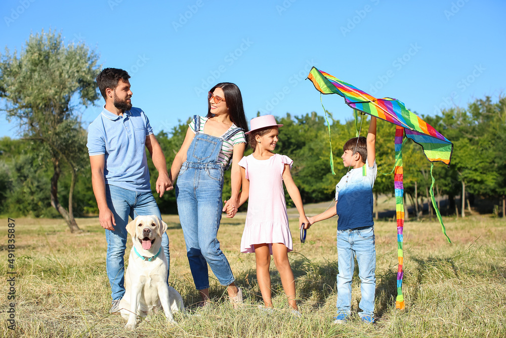 Happy family with cute dog and kite in park