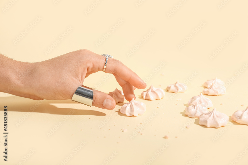 Female hand with sweet meringue on color background, closeup