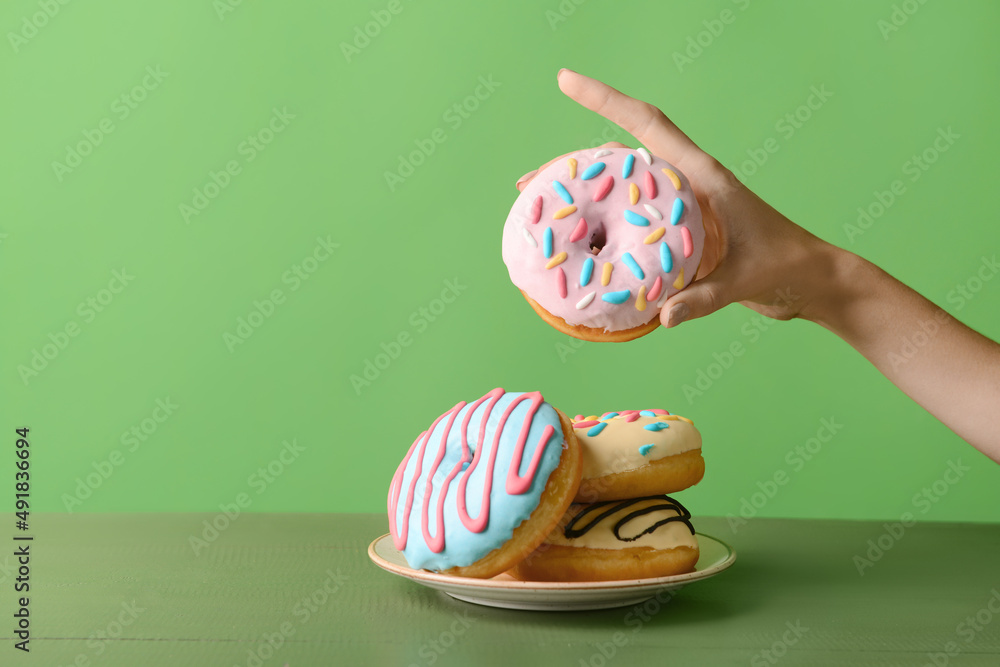 Woman holding delicious donut on green background