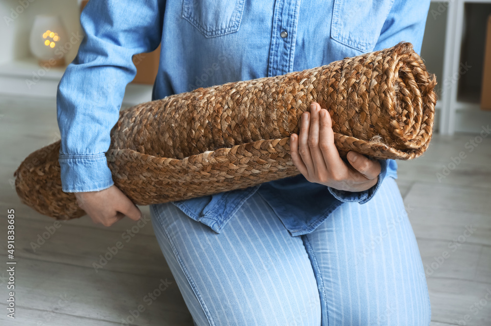 Young woman with rolled carpet at home