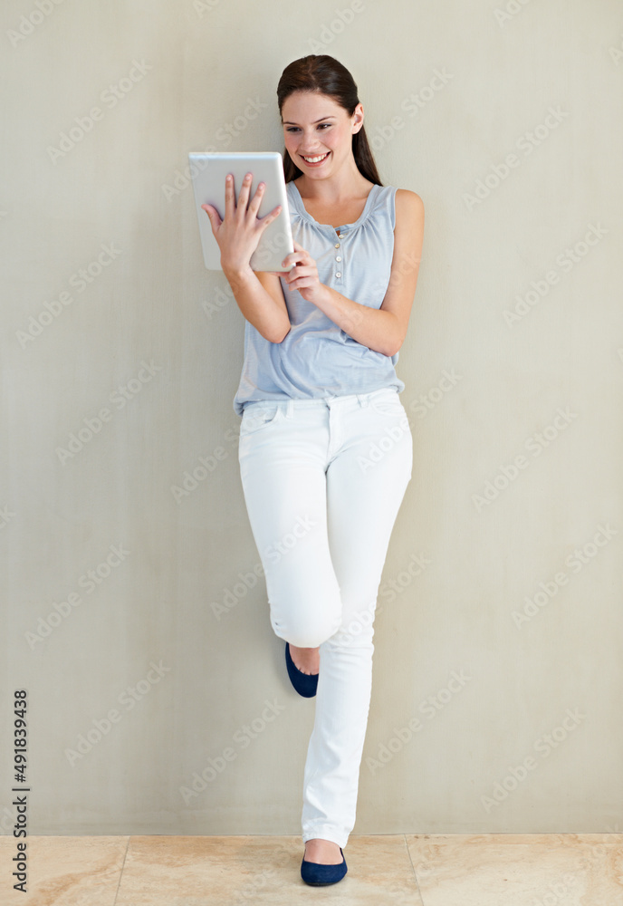 Blogging made easy. Full body of a beautiful young woman using her tablet.