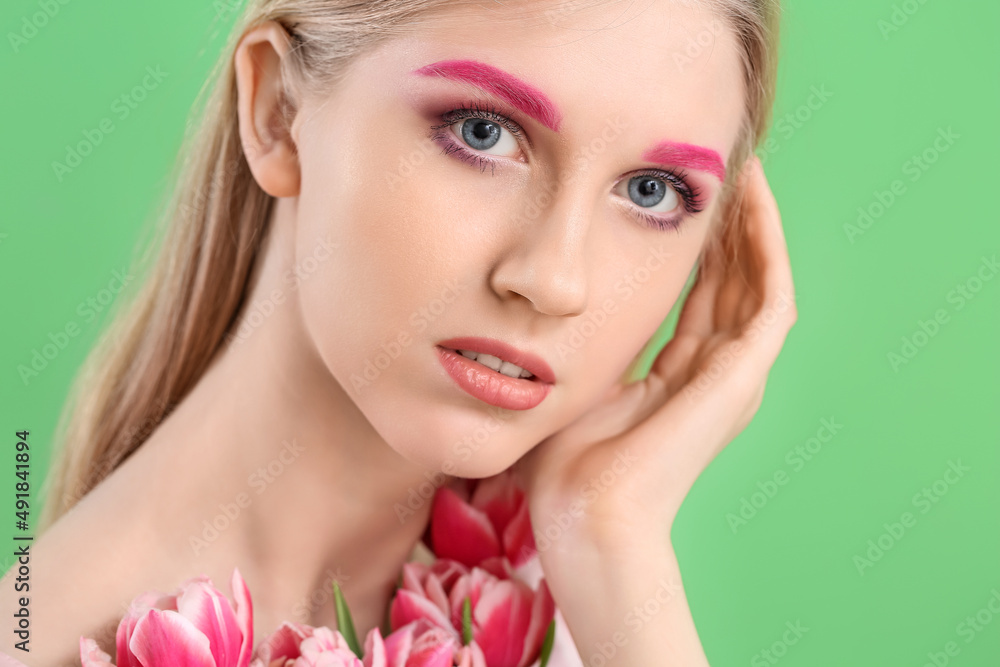 Portrait of woman with creative makeup and beautiful tulips on green background