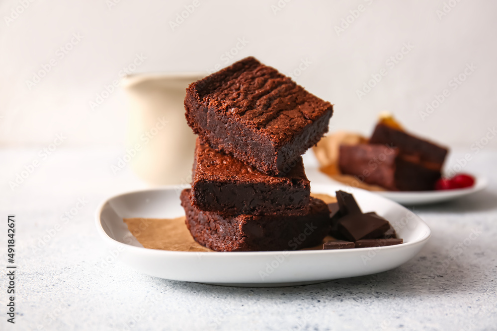 Plate with pieces of delicious chocolate brownie on light background