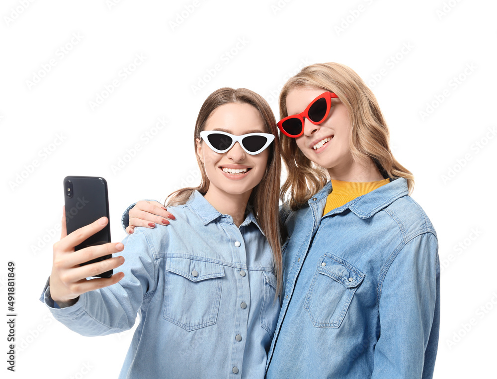 Portrait of young sisters taking selfie isolated on white