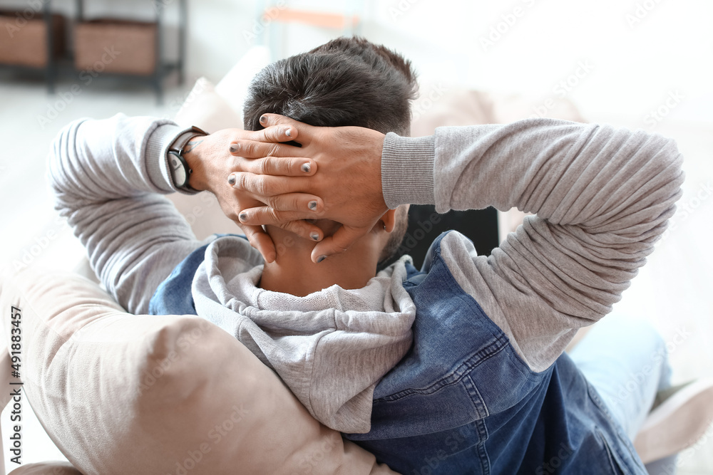 Young man with trendy manicure relaxing on sofa in light room