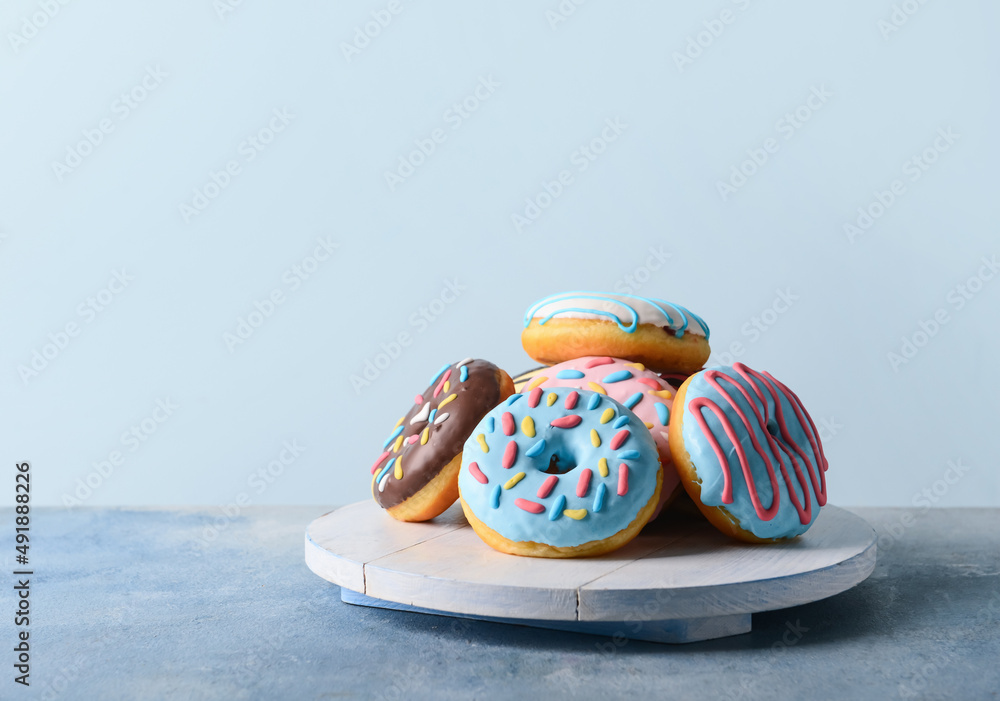 Board with different delicious donuts on table