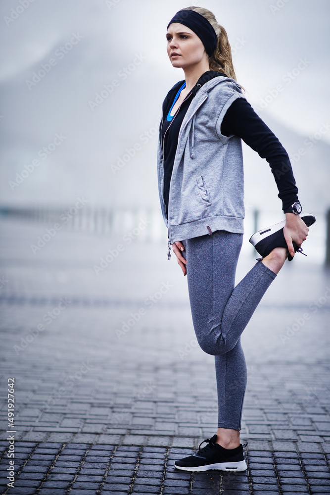 Motivated to get fit. Shot of a young woman stretching her legs before a run.