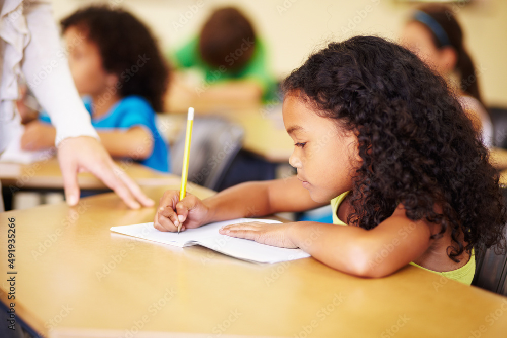 Fantastic work. A cute little girl smiling as she does her homework in class.