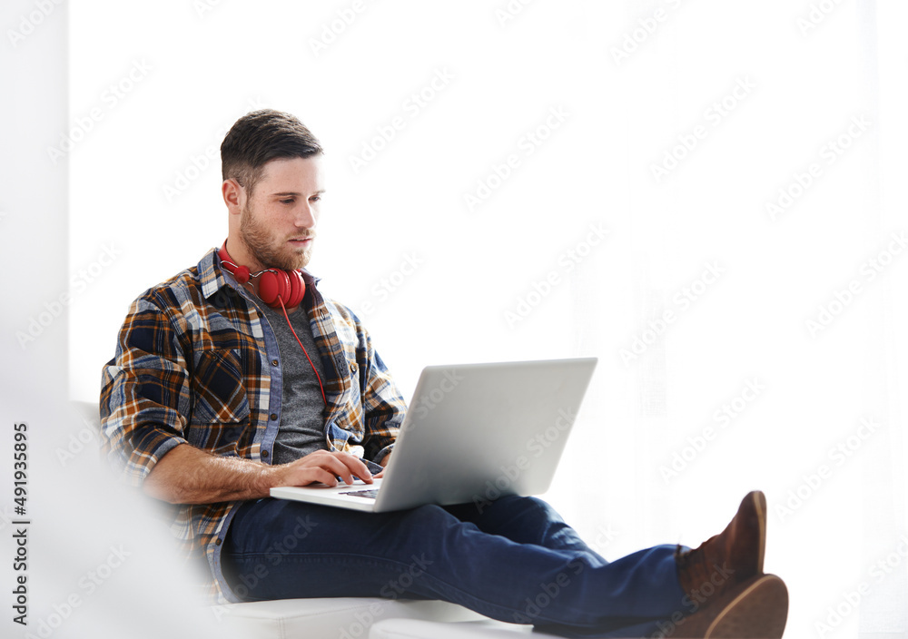 This is how I like to do chill. Shot of a young man using a laptop while relaxing at home.