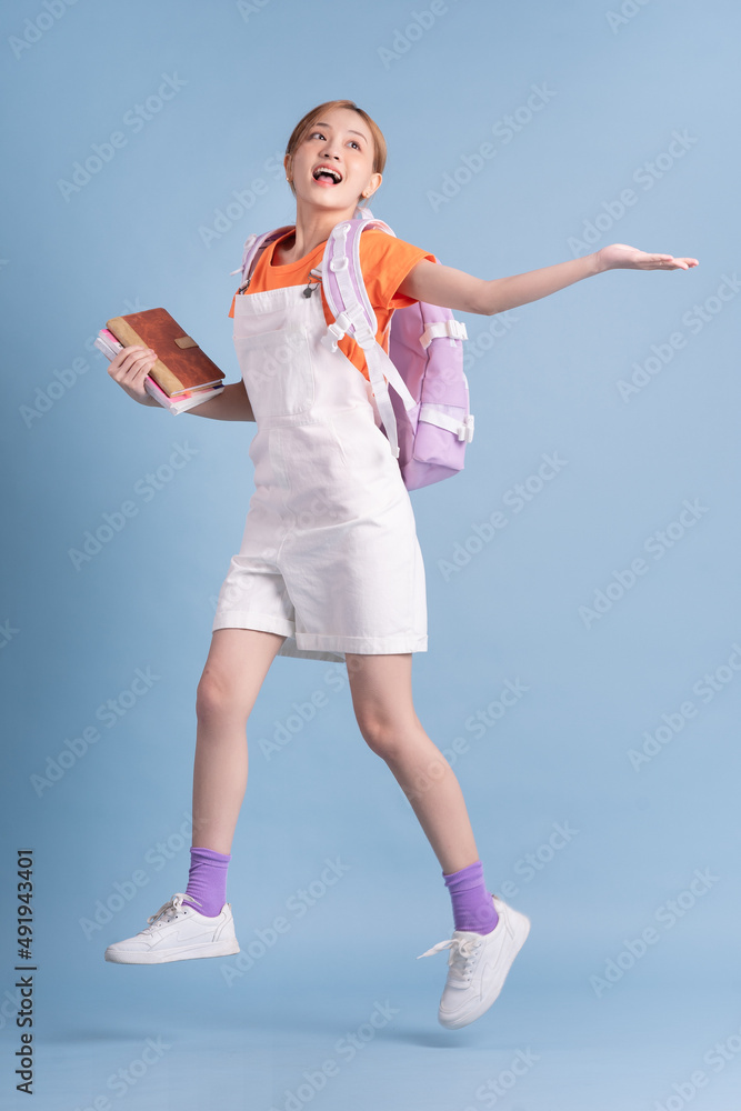 Young Asian student posing on blue background