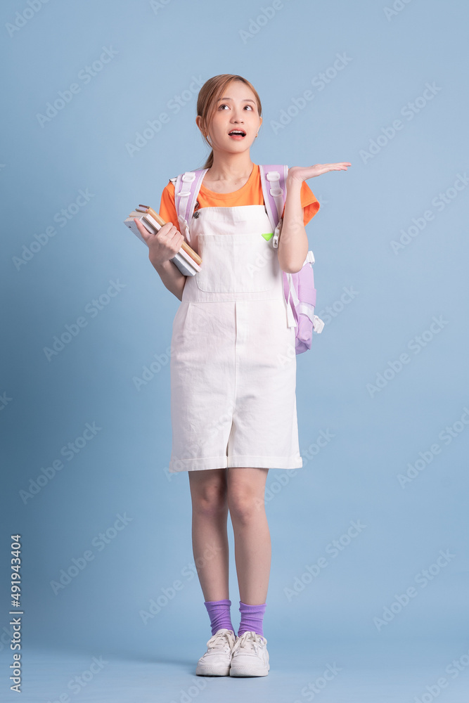 Young Asian student posing on blue background