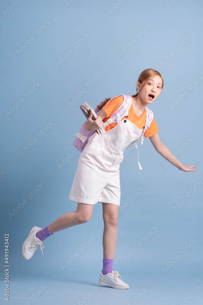 Young Asian student posing on blue background