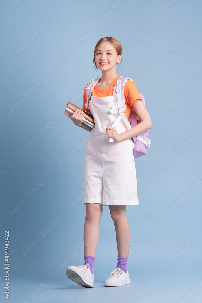 Young Asian student posing on blue background