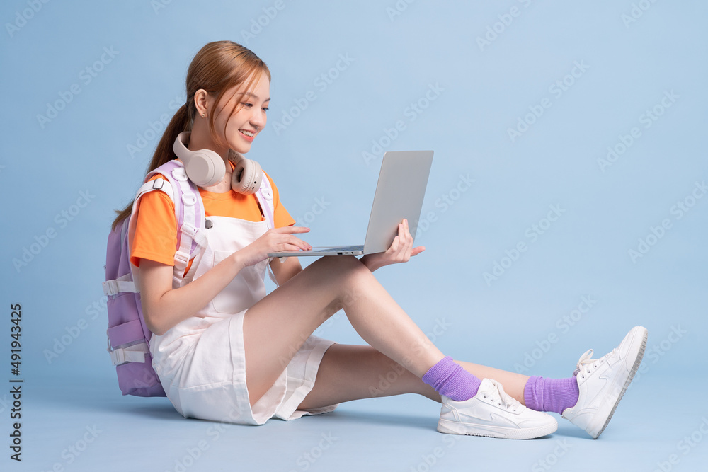 Young Asian student posing on blue background