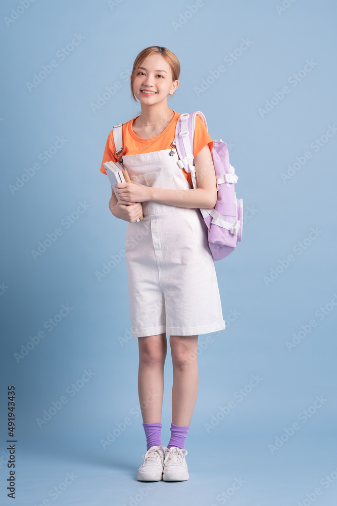 Young Asian student posing on blue background