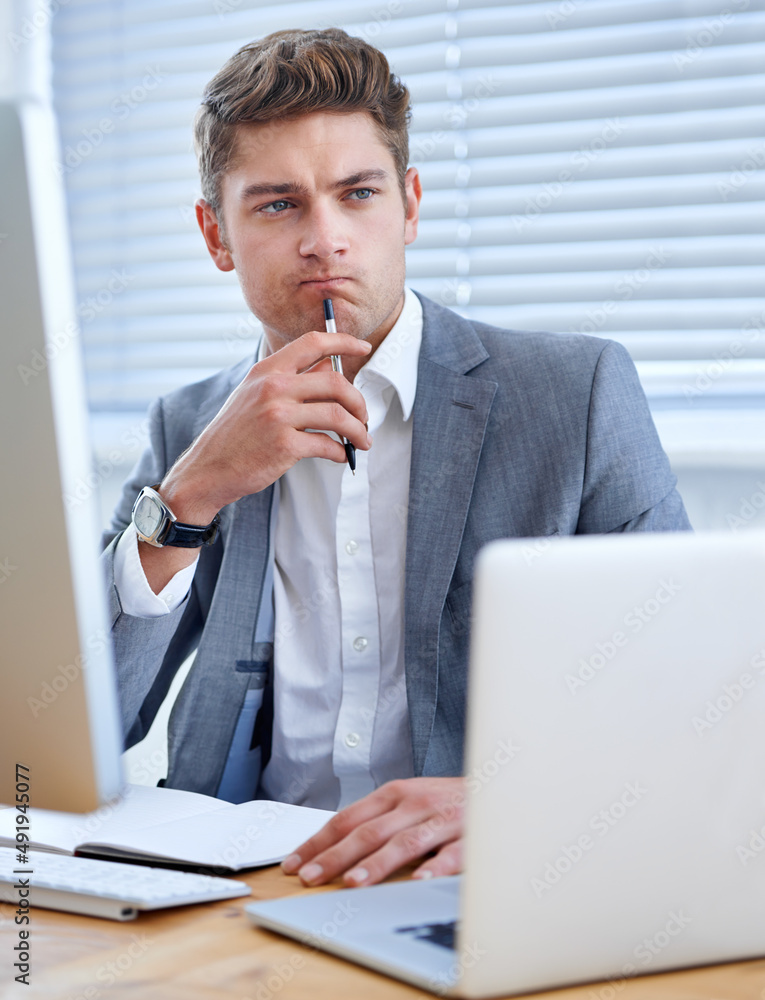 Using technology to compete work tasks. A handsome young businessman working in his office.