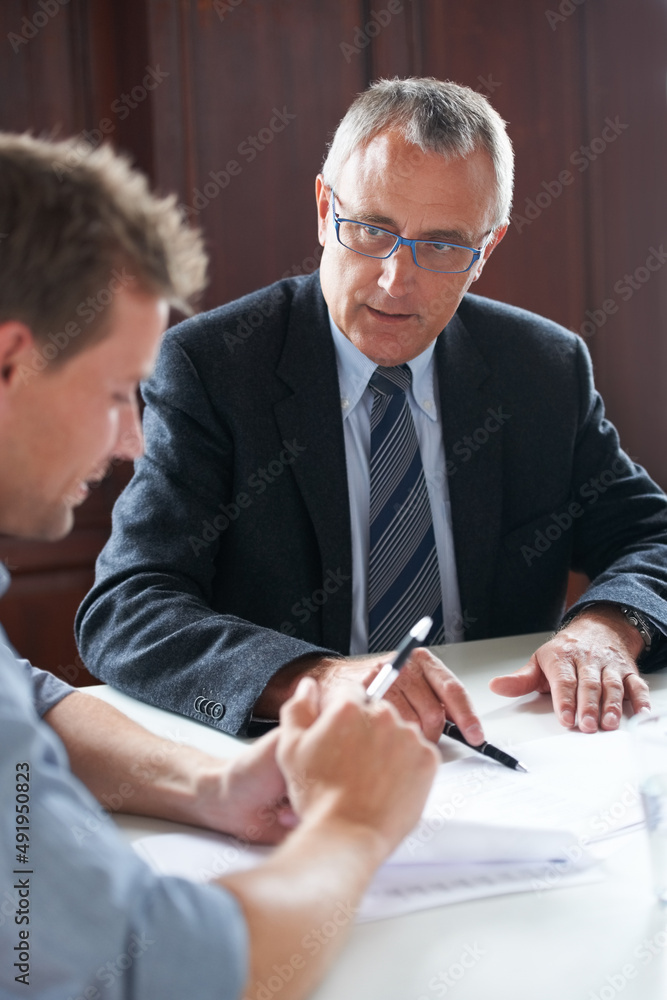 Going over assets. Shot of two colleagues discussing paperwork together.