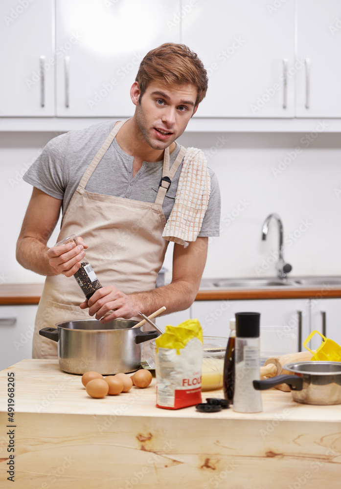 Season to taste. Cropped shot of a handsome young man cooking in the kitchen.