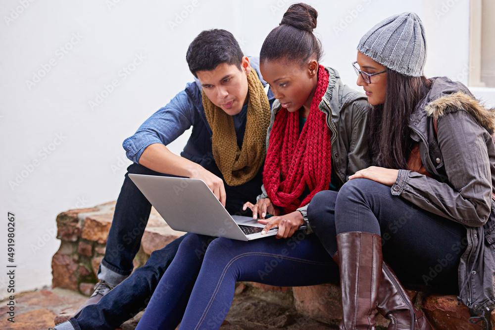 Busy with their latest homework assignment. Shot of a group of university students using a laptop wh