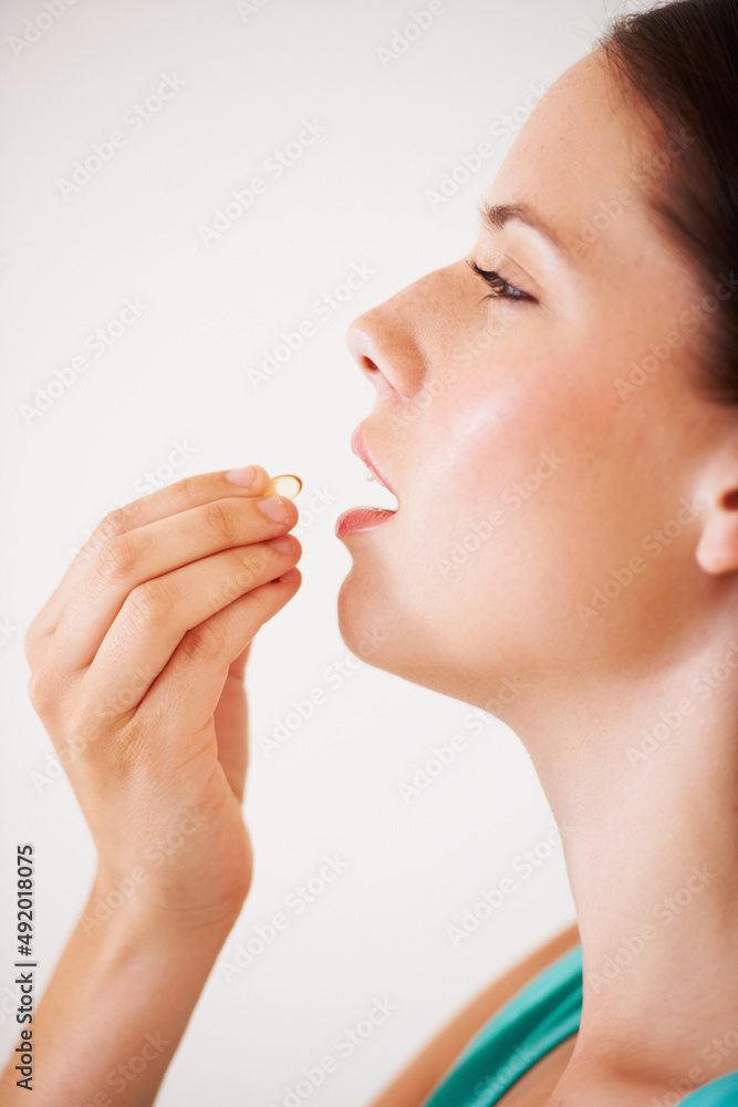 Boosting her immune system with a vitamin. Profile of an attractive young woman about to take a vita