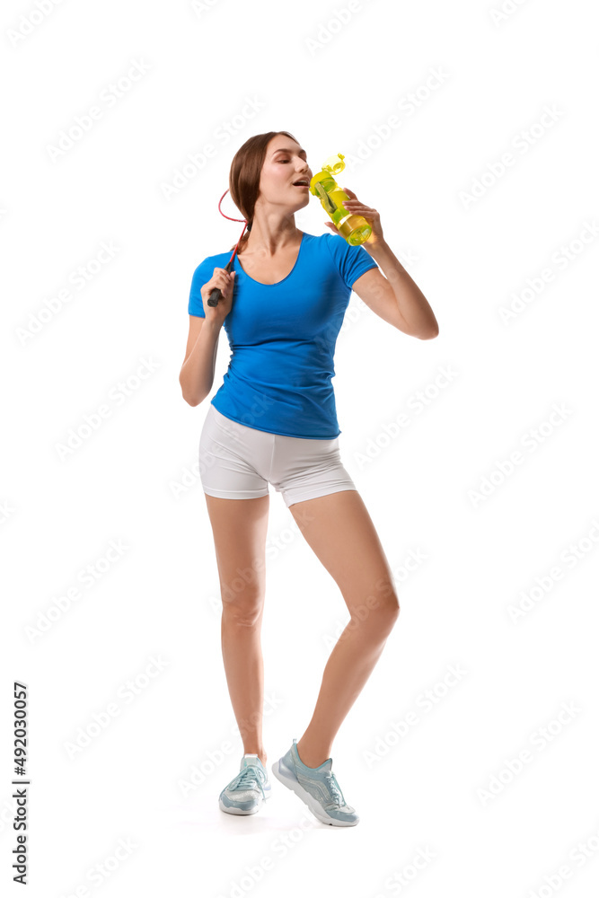 Sporty female badminton player drinking water on white background