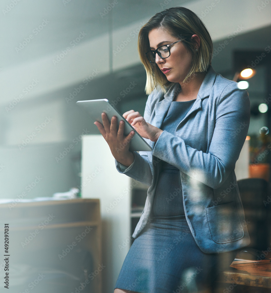 Utilizing smart tools to beat the deadline. Shot of a young businesswoman working late on a digital 