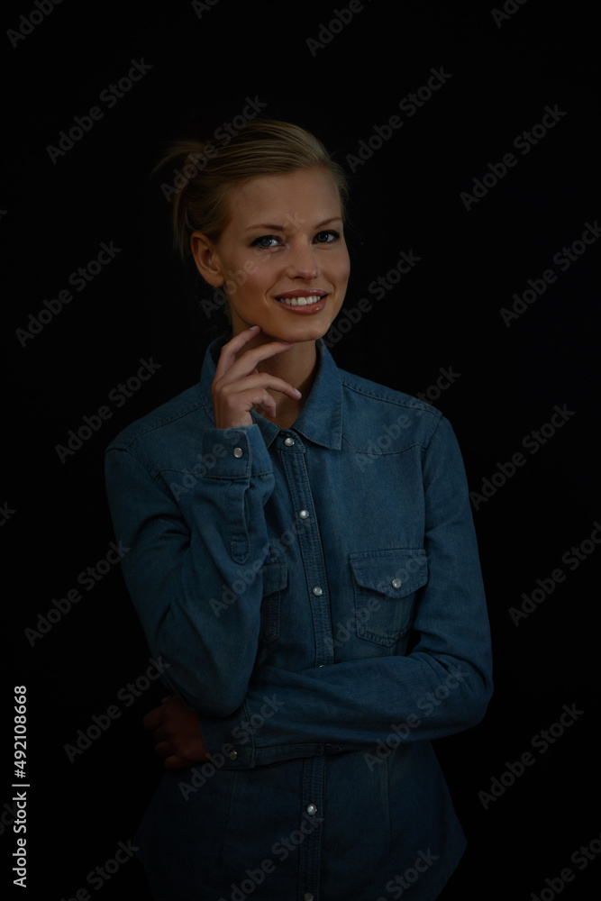 Positive thoughts brighten up a dark world. A young woman standing with her hand on her chin wearing