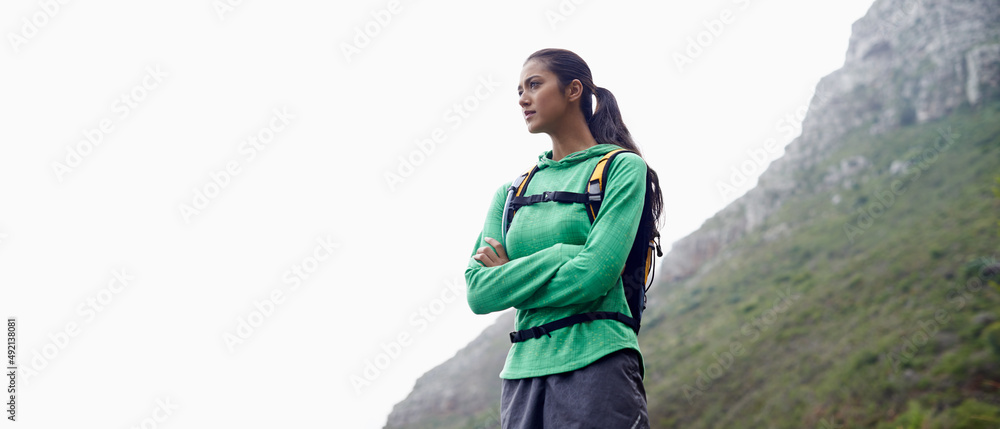 她喜欢越野跑。一个美丽的年轻女子站在风景优美的群山背景下。