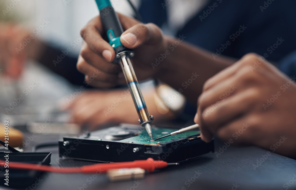 The master at making any computer hardware work. Shot of a technician using a soldering iron .to rep