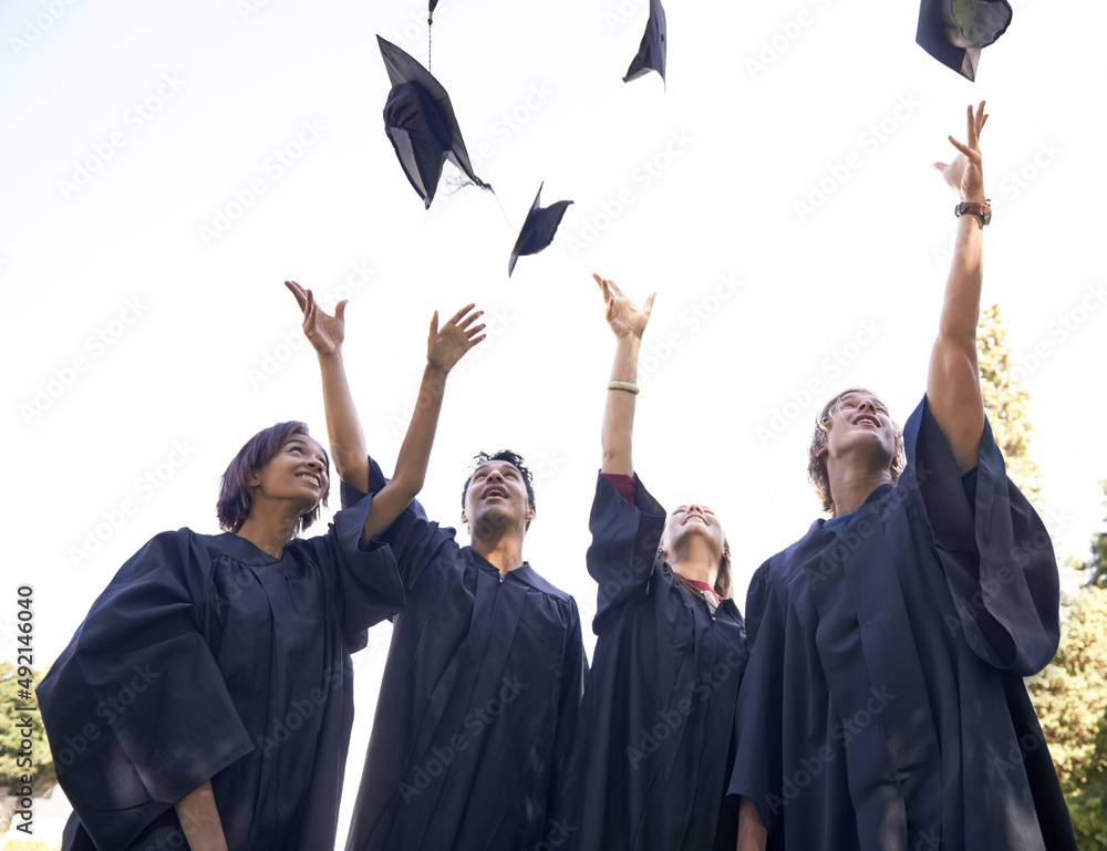 Our hard work has paid off. A group of university graduates throwing their hats in celebration.