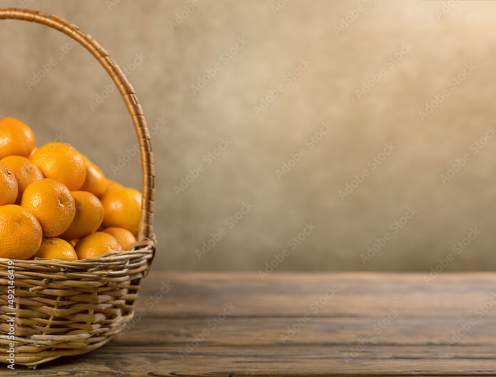 Ripe tangerines in a basket with a place to copy on a wooden background. Selective focus.