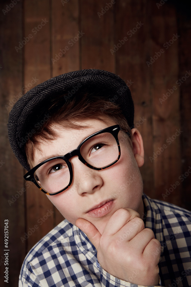 Thinking things through. Young boy in retro clothing wearing spectacles with a thoughtful expression