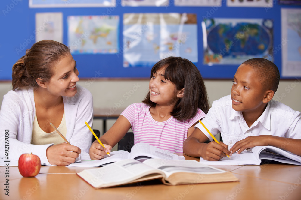 Giving some positive reinforcement. A young teacher having a discussion with her two ethnic pupils w