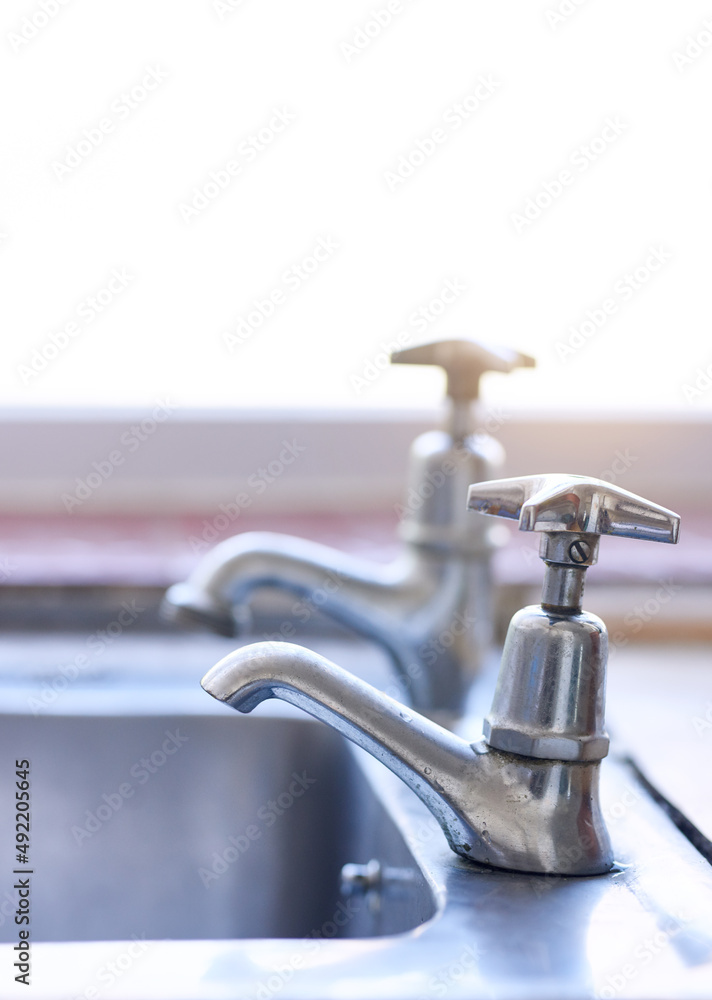 Water is in short supply. Shot of two dripping taps waisting a little bit of water in a basin inside