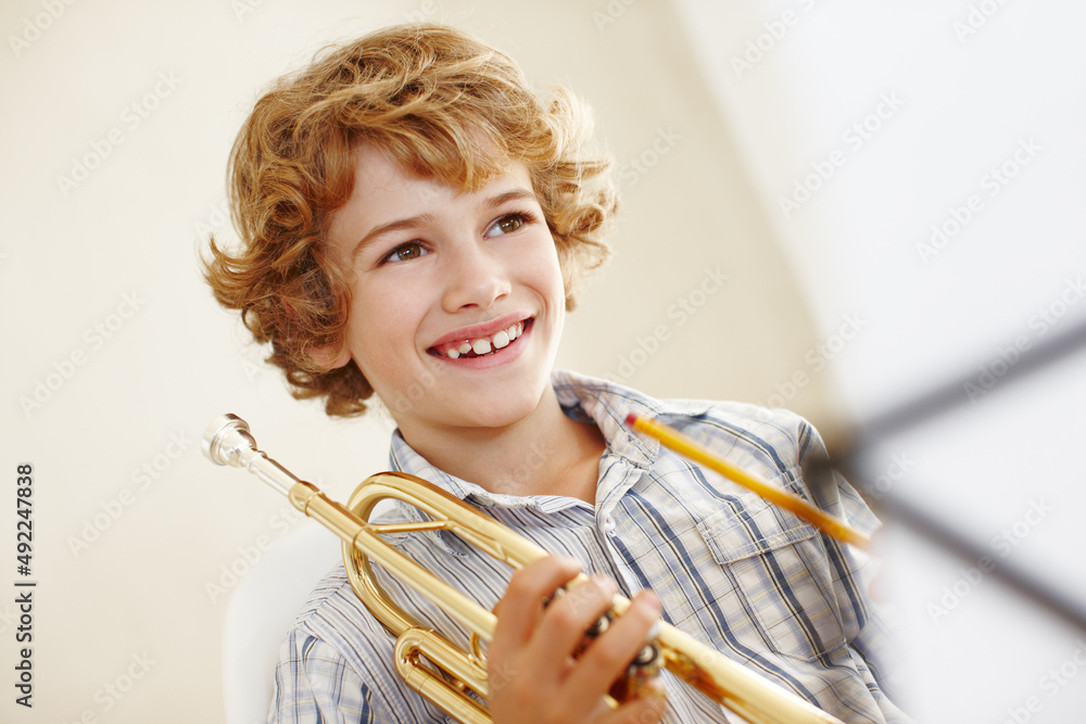 Following his musical dream. Shot of a cute little boy playing the trumpet.