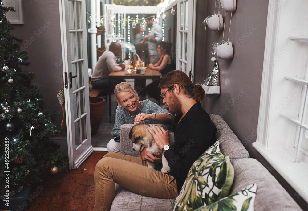 Can we keep it. Cropped shot of two cheerful friends hanging out together with a puppy in the living