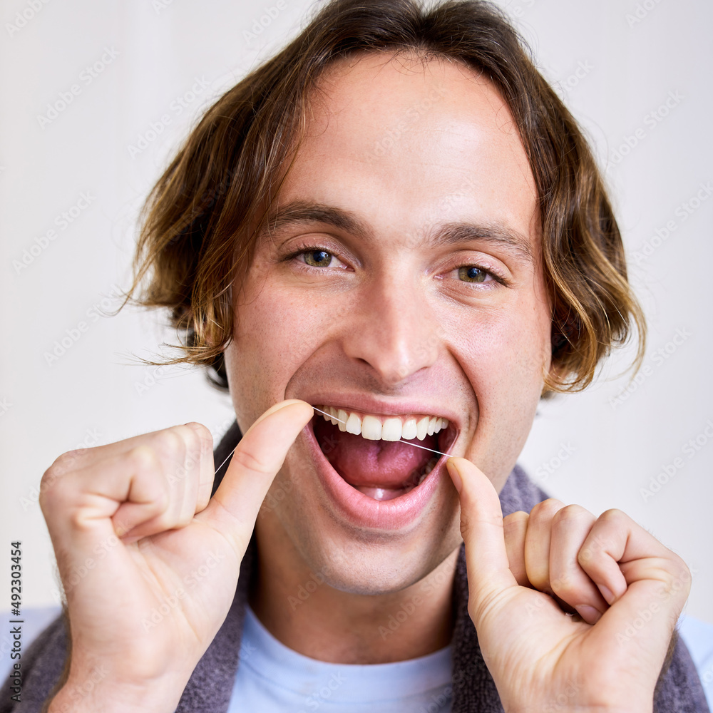 Make sure you get in between those teeth. Shot of a young man flossing his teeth.